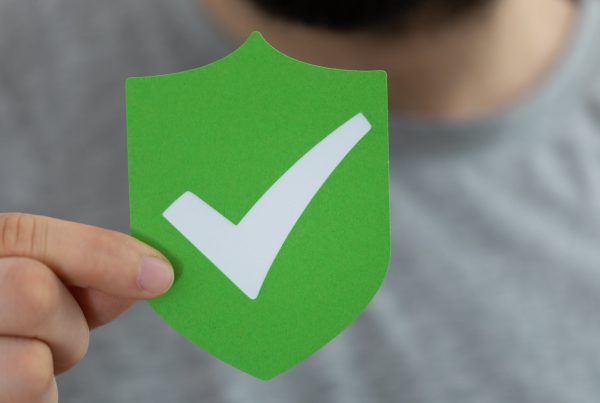 A man holds a green badge showing SARS compliance