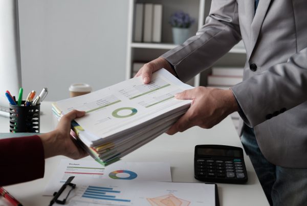 Close up view of businessman handing work document to his boss, working in the office room.
